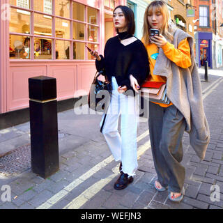 London, England, UK. Two young Japanese women with mobile phones Stock Photo