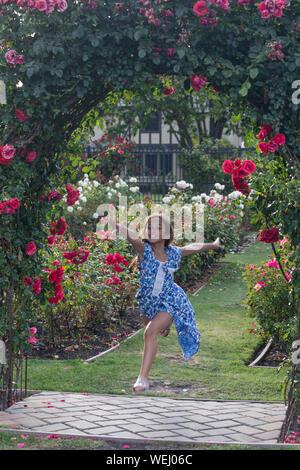 Preteen girl of Asian appearance doing gymnastics in rose garden, San Jose, California Stock Photo