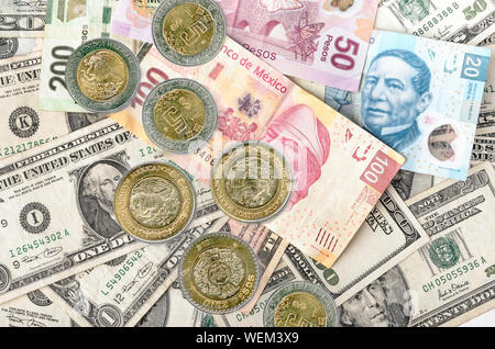 Mexican Peso Coins over assorted Dollars and Mexican Peso bills cash pile. Stock Photo