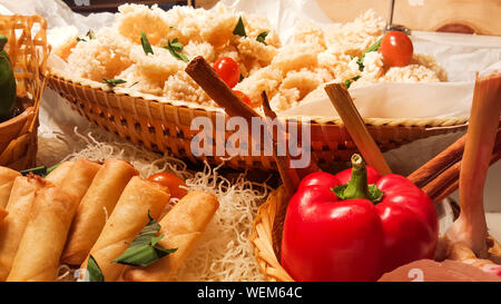 Many of salty snack that including crispy rice, fried spring rolls, tomato and pretzels served as party food in the wooden bar Stock Photo