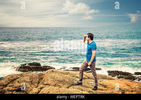 man in casual clothing next to the sea looking at the horizon Stock Photo