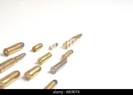 A large bullet leading several smaller bullets laying over a white surface. It works as a concept for leadership, crime, arms race.