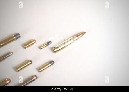 Large bullet leading several smaller bullets laying over a white surface. It works as a concept for leadership, crime, arms race.