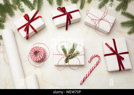Christmas giftbox and presents wrapping in craft paper and decor on wooden board. Flat lay. Top view. Creative hobby. Stock Photo