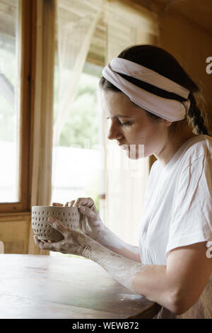 Beautiful young woman in a creative workshop sits at a table Stock Photo