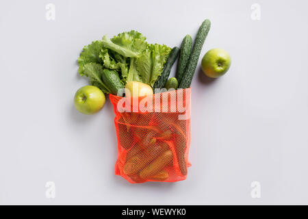 Zero waste concept. Orange shopping mesh bag with green vegetables. Top view. Stock Photo