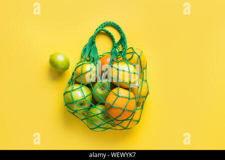 Shopping string bag with friuts, lemon, orange on yellow. Zero waste concept. Space for text. View from above. Stock Photo