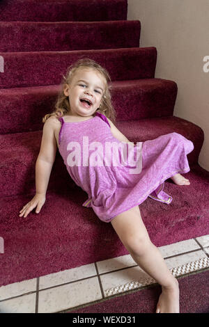 Lily playing on the entryway stairwell in her home Stock Photo