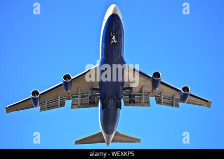 A British Airways Boeing 747 on final approach with its wheels down against a blue sky in New York Stock Photo