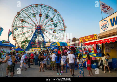 NEW YORK CITY - JULY, 2017: Thrill seekers crowd the colorful amusement park on the boardwalk at Coney Island in Brooklyn. Stock Photo