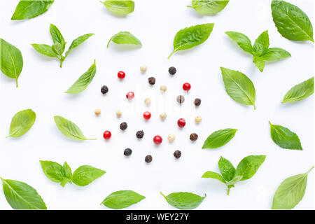 Basil leaves with  different type of peppercorns on white background. Top view Stock Photo