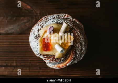 Stylish Easter cake with marshmallows and jelly bears on a dark rustic wooden background, Seasonal greetings for Easter. Copy space. view from above. Stock Photo