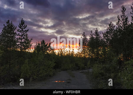 Cumulus sunset clouds with sun setting down. The sky with dark clouds illuminated by the setting sun. Stock Photo