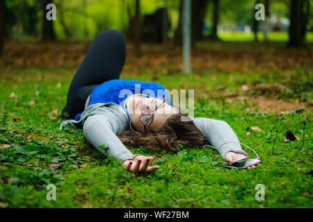 Portrait Of Teenage Girl Lying On Field At Park