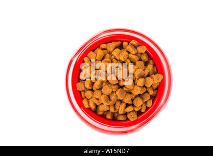 Red pet feeder. Bowl filled with dried food. Kibble on isolated white background Stock Photo
