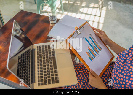Businesswoman holding and analyzing sales statistics data document  Stock Photo