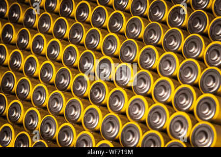 Close view of batteries alkaline 1.5 Volts in size AA Several batteries in rows.A close-up of the same yellow batteries, lined up in even rows by posi Stock Photo