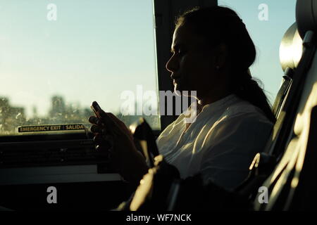 New York City, New York / USA - June 27, 2019: Indian woman taking the bus into the city late in the afternoon Stock Photo