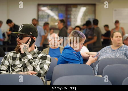 Wethersfield, CT / USA - June 11, 2019: Snapshot of a bored crowd of people in the waiting area (focus on tattooed caucasian man) Stock Photo