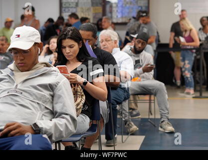 Wethersfield, CT / USA - June 11, 2019: Snapshot of a bored crowd of people in the waiting area (focus on black-haired woman) Stock Photo