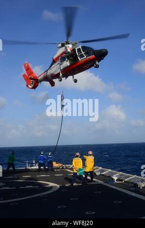 Crewmembers aboard the Coast Guard Cutter Stratton (WMSL 752) practice in-flight refueling with an MH-65 Dolphin helicopter Aug. 28, 2019, while the Stratton transits the Bay of Bengal. The operation was part of routine training and qualification experience for crewmembers of Stratton. (U.S. Coast Guard photo by Petty Officer 1st Class Levi Read) Stock Photo