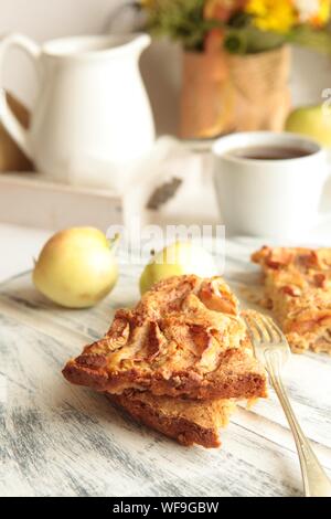Freshly baked tasty apple pie with apples and tea cup in the background. Homemade healthy food concept. Stock Photo