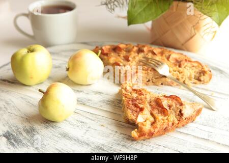 Freshly baked tasty apple pie with apples and tea cup in the background. Homemade healthy food concept. Stock Photo