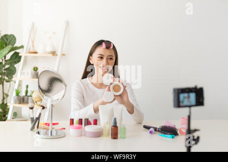 Young woman professional beauty vlogger or blogger recording cosmetic makeup tutorial with camera to share on social media Stock Photo