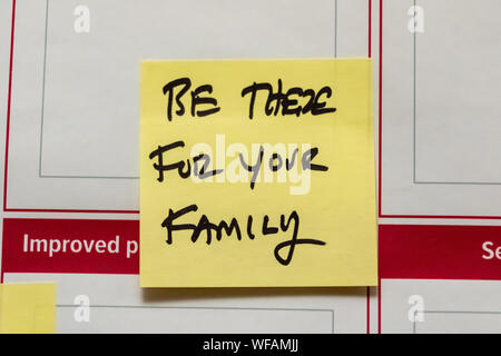 Yellow sticker note written Be there for your family with a marker Stock Photo