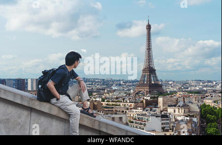 a man with backpack looking at Eiffel tower, famous landmark and travel destination in Paris, France Stock Photo