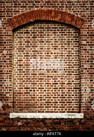 Old bricked-up window with arch. Architectural feature in red brick with white stone windowsill. Decorative frame with space for text Stock Photo