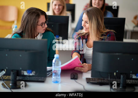 Two students smiling girl on class with computer on university campus Stock Photo