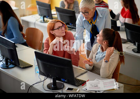 teacher helping smiling students on project Stock Photo