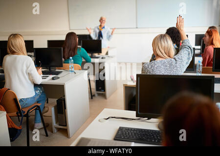 Smiling students asking question while attending professor in campus Stock Photo