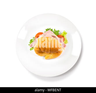 Big croissant with green salad and pork meat on isolate white background. Tasty croissant with a fork and dark place beside the plate Food photo. Heal Stock Photo