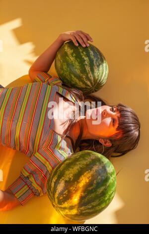 Woman lying on the floor next to two watermelons Stock Photo