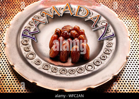 Dried dates on metal plate with ramadan inscription Stock Photo