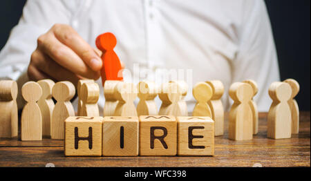 Wooden blocks with the word Hire. Headhunter selects a person from the crowd. Human Resource Management. Recruiting Headhunting. Hiring employees. Bus Stock Photo