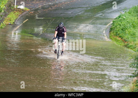 Bardowie, Glasgow, Scotland, UK. 31st Aug, 2019. UK weather - a determined cyclist continues his morning ride regardless of the sections of flooding due to heavy rain overnight and showers this morning in Glasgow Credit: Kay Roxby/Alamy Live News Stock Photo