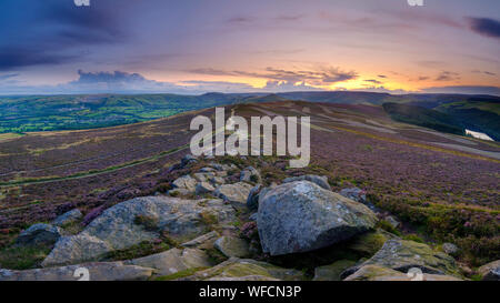 Win Hill, UK - Aug 12, 2019:  Colourful sunset over the Peak District from Win Hill with the beginnings of heather blossoming. Stock Photo