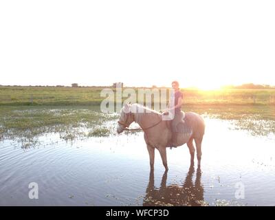 Young Woman Horseback Riding In Farm Against Clear Sky During Sunny Day
