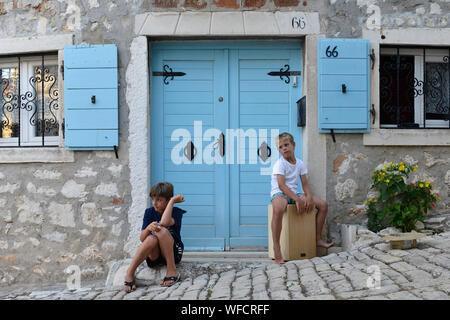 Two local boys hanging around in front of their home in the streets of Rovinj, Istria, Croatia, Europe. Stock Photo