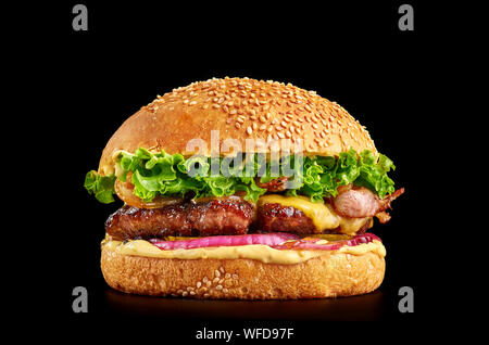 burger at black background with beef or pork cutlet or steak with onion, cheese, bacon, lettuce and mustard sauce in white bun with sesame Stock Photo