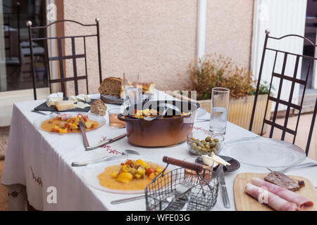 served dinner table homemade dishes cooked vegetables and appetizers white tablecloth minimum decor Stock Photo