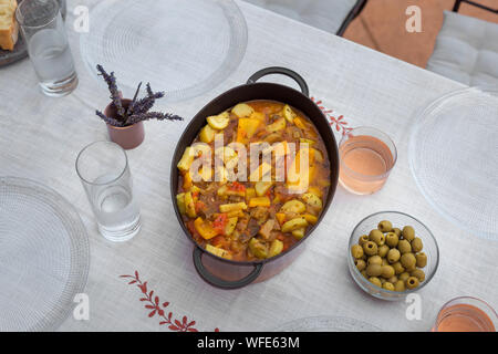 served dinner table homemade dishes cooked vegetables and appetizers white tablecloth minimum decor Stock Photo