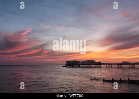 Cromer Pier at dawn and sunrise, with rainbow colours across the sky Stock Photo