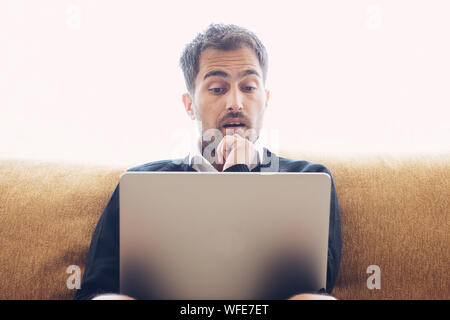 Confused surprised young man using a pc laptop computer Stock Photo
