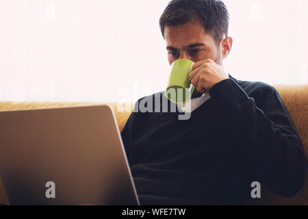 Young man working at home and drinking a cup of coffee Stock Photo