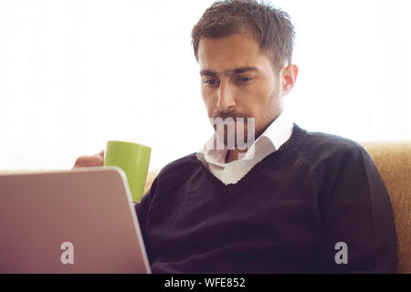 Young man working at home and drinking a cup of coffee Stock Photo