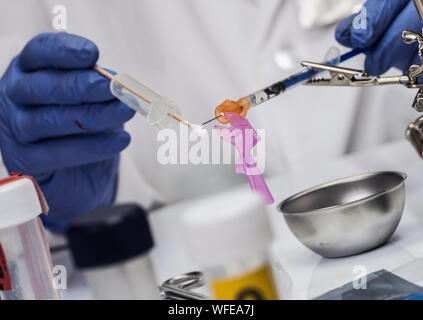Specialized police analyzes syringe with traces of blood from a victim overdose with tweezers, conceptual image Stock Photo